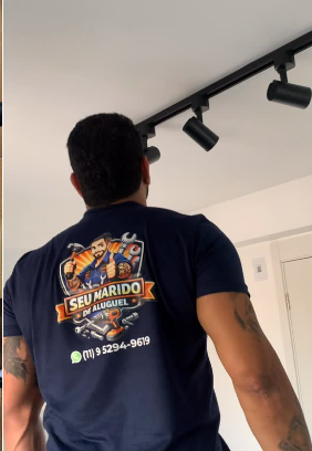 Profissional com uniforme da marca ajustando trilho de iluminação